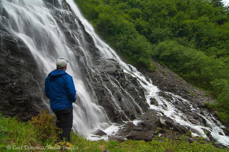A hiker stands alongside Horsetail Falls, near Valdez, on the Richardson Highway, Alaska.