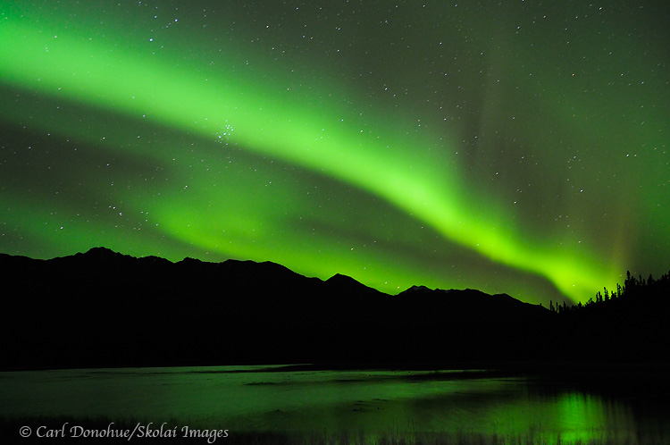 The aurora borealis (northern lights) light up the night sky and a reflection glows in Dead Dog Hill Lake in the Mentasta Mountains, boreal forest, Wrangell-St. Elias National Park and Preserve, Alaska.